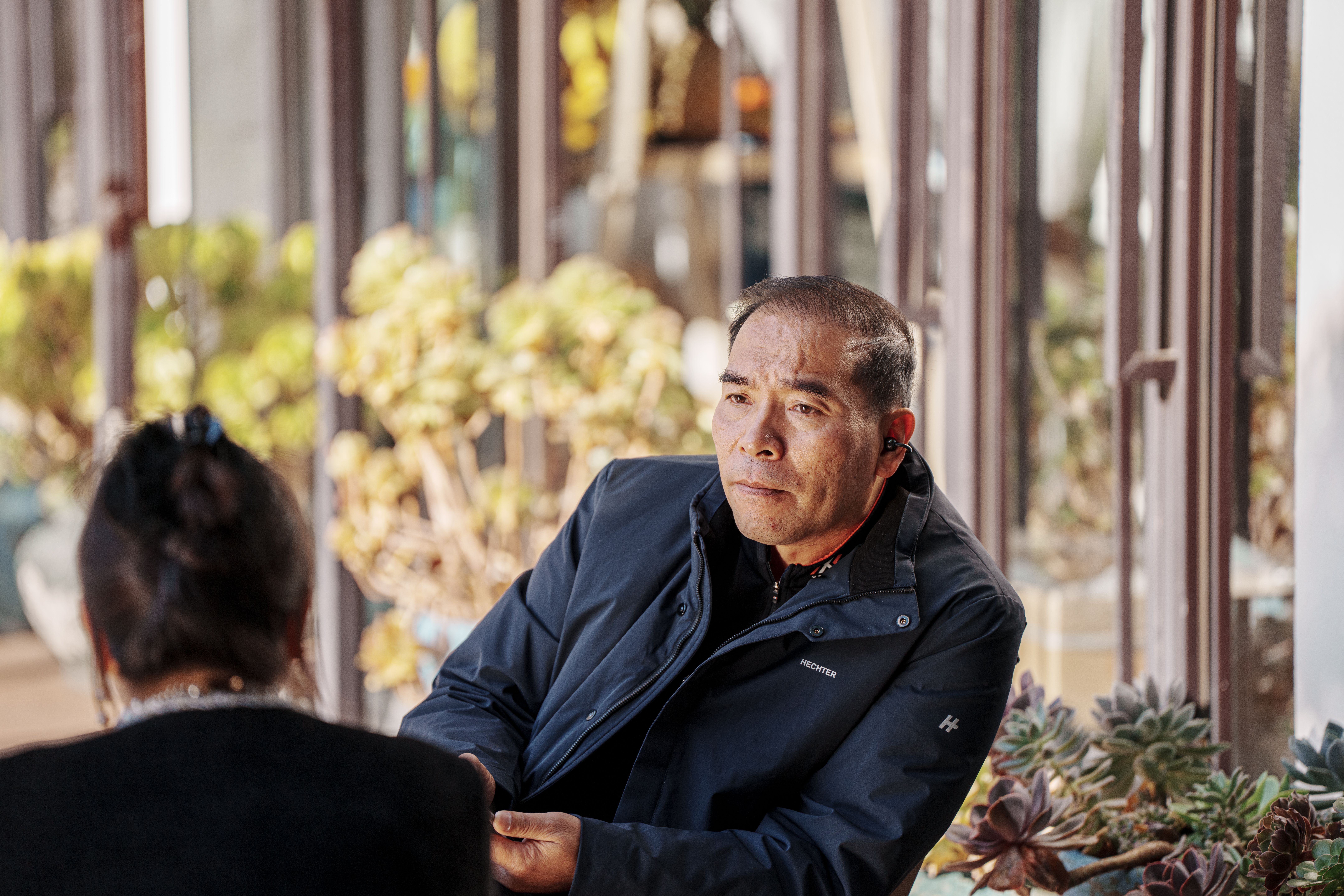 Two adults share an attentive conversation at a sunny cafe, illustrating the value of paid companionship and face-to-face connection.